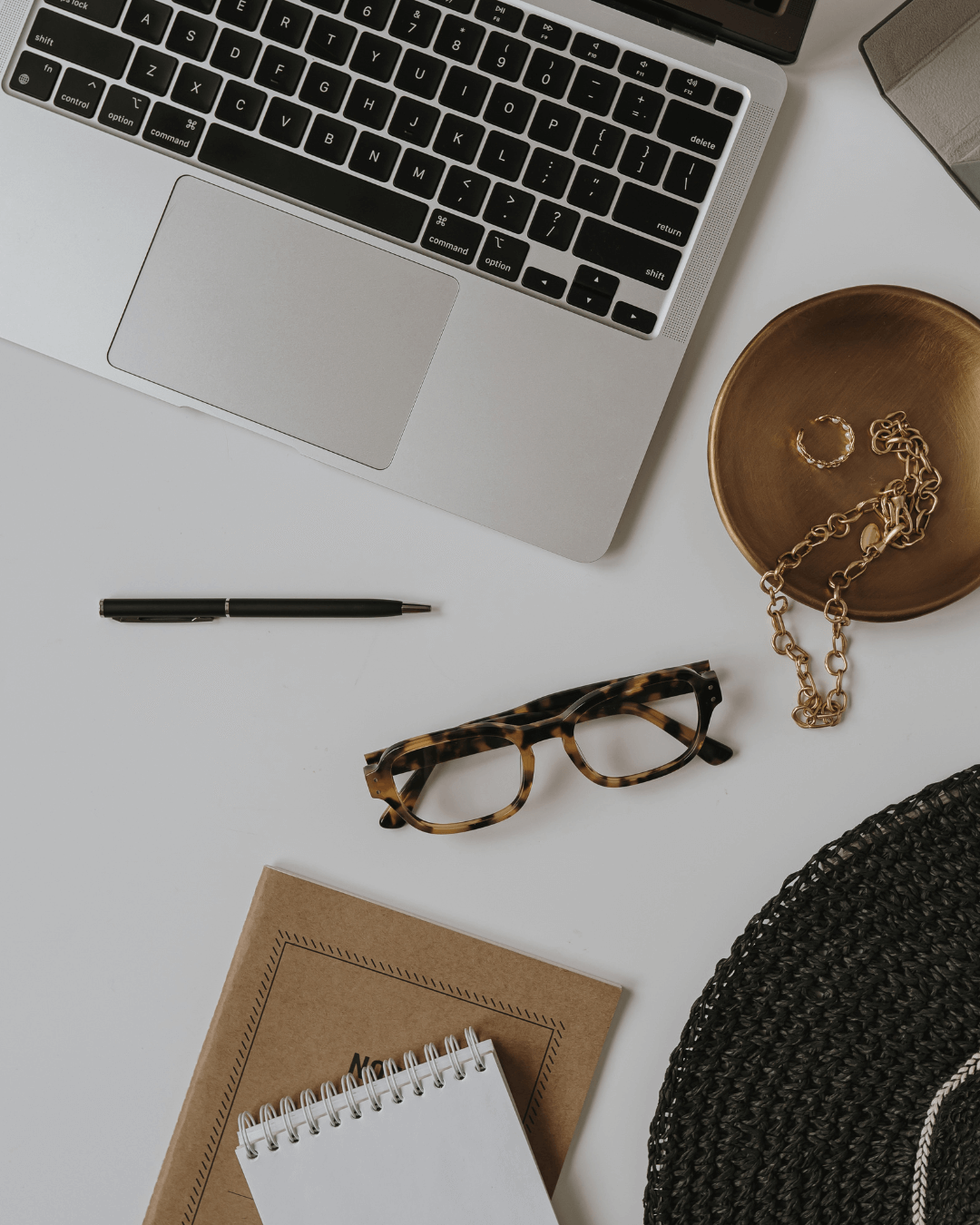 Laptop and a pair of glasses resting on a wooden table, surrounded by various office supplies.